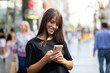 © Adam Radosavljevic - Beautiful smiling woman in black shirt texting on smartphone on street in city center