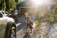 Little Girl On Her Bicycle In Her Driveway With Friends In Summer