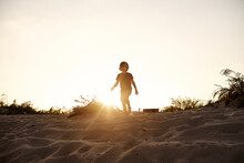Silhouette Of A Little Boy Running In A Sandy Land