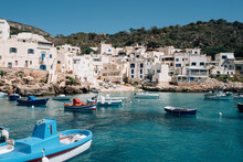 Blue Boat Floats In Blue Waters Of Levanzo Harbour By White Houses
