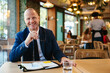 © BONNINSTUDIO/Stocksy - Positive businessman sitting at restaurant table