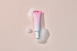 © Marc Tran/Stocksy - pink cosmetic tube on a beige background with soap foam and bubbles.