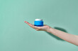 © Marc Tran/Stocksy - beautiful female hand holding a jar of cream on a blue