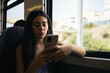 © Pedro Merino/Stocksy - Young woman using smartphone traveling by train