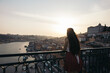 © Pedro Merino/Stocksy - Young woman watching Porto city from the bridge