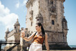 © Pedro Merino/Stocksy - Young tourist woman taking selfies with her smartphone at Belem tower