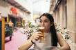 © Pedro Merino/Stocksy - Young woman drinking beer on a bar terrace