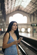 © Pedro Merino/Stocksy - Girl waiting for the train at the station using smartphone