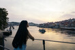 © Pedro Merino/Stocksy - Young woman enjoying the views of the riverbank at sunset.