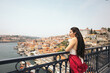 © Pedro Merino/Stocksy - Young woman watching Porto city from the bridge