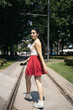 © Pedro Merino/Stocksy - Young woman in a red skirt walking happily down the street