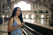 © Pedro Merino/Stocksy - Girl waiting for the train at the station using smartphone