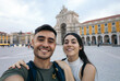 © Pedro Merino/Stocksy - Couple of friends taking a selfie in the Commerce Plaza in Lisbon