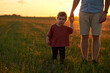 © Elenka Kharichka/Stocksy - Baby girl walks hand in hand with dad at sunset