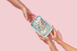 © Yaroslav Danylchenko/Stocksy - Saved dollars passing from hands to hands.