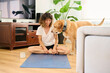 © Guille Faingold/Stocksy - Happy woman with dog doing yoga