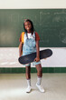 © Santi Nuñez/Stocksy - Portrait of Student holding a skateboard