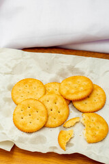 Wall Mural - Snack concept, Crackers or biscuit stack in parchment paper with cracker scrap on wooden background