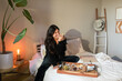 © ByLorena/Stocksy - Young woman having breakfast at bedroom