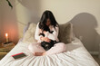 © ByLorena/Stocksy - Brunette woman holding cute black dog in bedroom