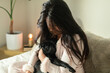 © ByLorena/Stocksy - Brunette woman holding cute pug in bedroom