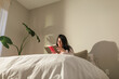 © ByLorena/Stocksy - Young woman on duvet reading in bedroom