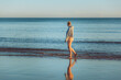 © Helen Rushbrook/Stocksy - Teenage girl walking on a beach at dusk
