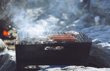 Frankfurters And Burgers On A Charcoal Grill On The Beach