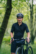 © Daniel Gonzalez/Stocksy - Happy guy smiling near gravel bicycle in woods