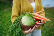 © AD Astra Team/Stocksy - A woman holds a basket of vegetables from her garden