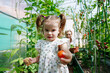 © AD Astra Team/Stocksy - Mom and daughter are picking vegetables in the greenhouse