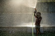 Boy Spraying Water In Golden Sunlight