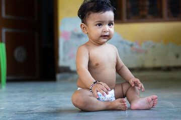 six months baby boy sitting on floor wear diaper only