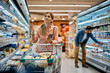 © Drazen - Happy woman using reminder on smart phone while shopping in supermarket.