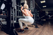 Leinwandbild Motiv Middle-aged fitness woman doing squat exercise in a gym