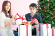 © themorningglory - Man giving  christmas present to his girlfriend and decorate christmas tree celebrate winter new year