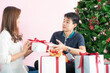 © themorningglory - Man giving  christmas present to his girlfriend and decorate christmas tree celebrate winter new year