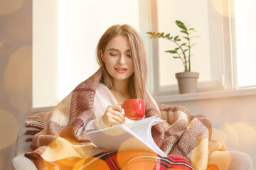 Canvas Print - Beautiful woman with cup of coffee reading book at home