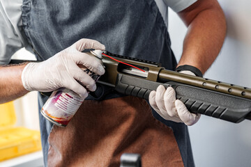 Sticker - Close up of a man in apron lubricates the mechanism of the weapon with oil