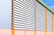 Perspective side view of aluminum louver with gutter drainage system outside of industrial building against blue sky background