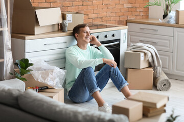 Wall Mural - Young man sitting in kitchen on moving day