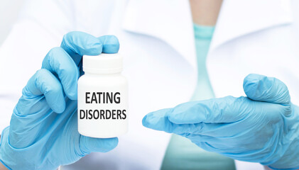 Wall Mural - eating disorders inscription on the label on the can in the hands of a doctor in blue gloves. Medical concept.