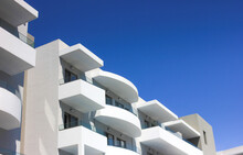 Image Of The Top Of A White Building With Balconies Against A Blue Sky On A Sunny Day. Architecture.