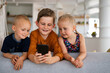 © NDABCREATIVITY - Childhood technology kids smartphone concept. Happy little children playing on mobile phone