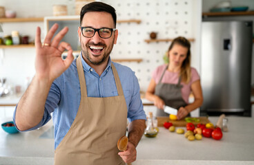 Wall Mural - Portrait of handsome happy man cooking at home preparing food in kitchen.