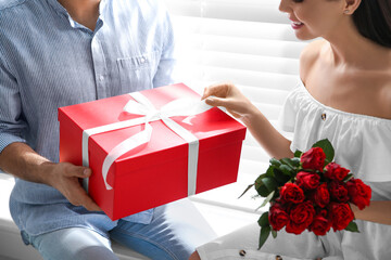 Wall Mural - Man presenting gift to his beloved woman at home, closeup. Valentine's day celebration