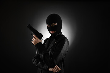 Woman wearing knitted balaclava with gun on black background