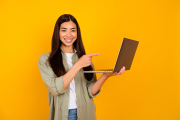 Wall Mural - Portrait of charming cheerful girl indicate finger wireless netbook isolated on yellow color background