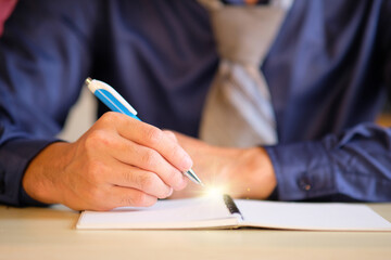 Sticker - Businessman writing notes while working on a computer in a modern office