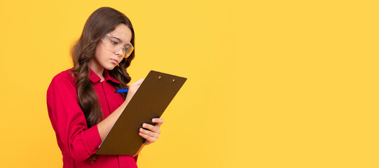 Sticker - concentrated teenager girl in protective glasses making notes in folder with documents. Child builder with protective glasses horizontal poster design. Banner header, copy space.